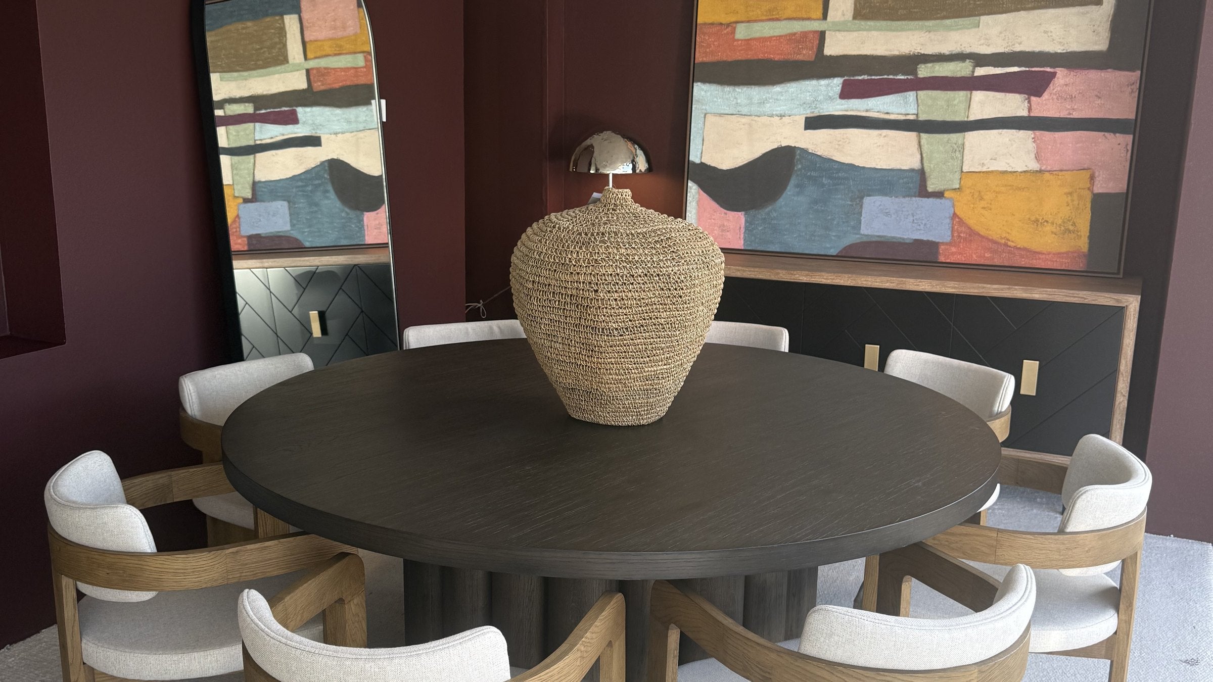 Translation missing: en.Round dark-wood dining table with oak and ivory upholstered chairs in the Viva showroom
