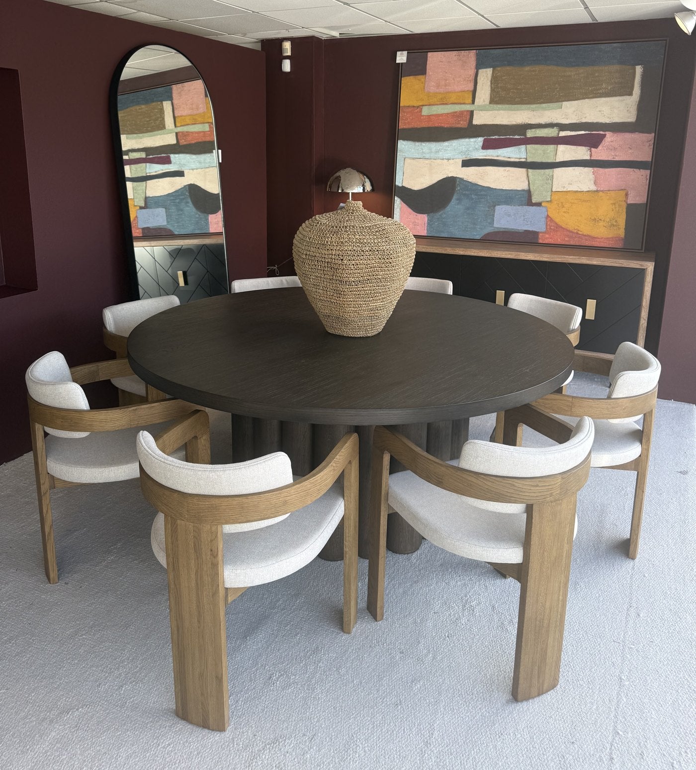 Translation missing: en.Round dark-wood dining table with oak and ivory upholstered chairs in the Viva showroom